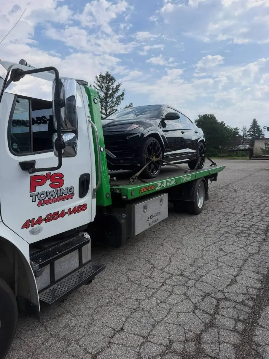 PS Towing truck carrying a black Lamborghini Urus
